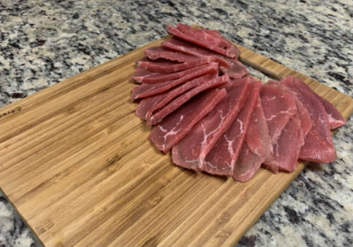 Thin raw beef slices spread across a cutting board
