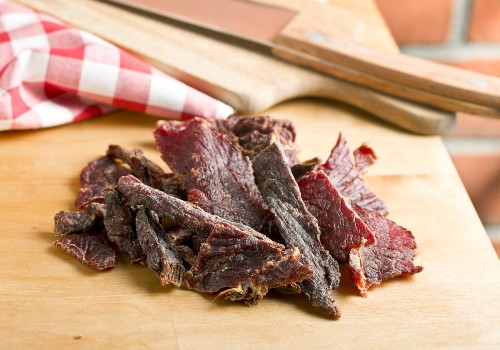 A small pile of beef jerky on a wooden cutting board