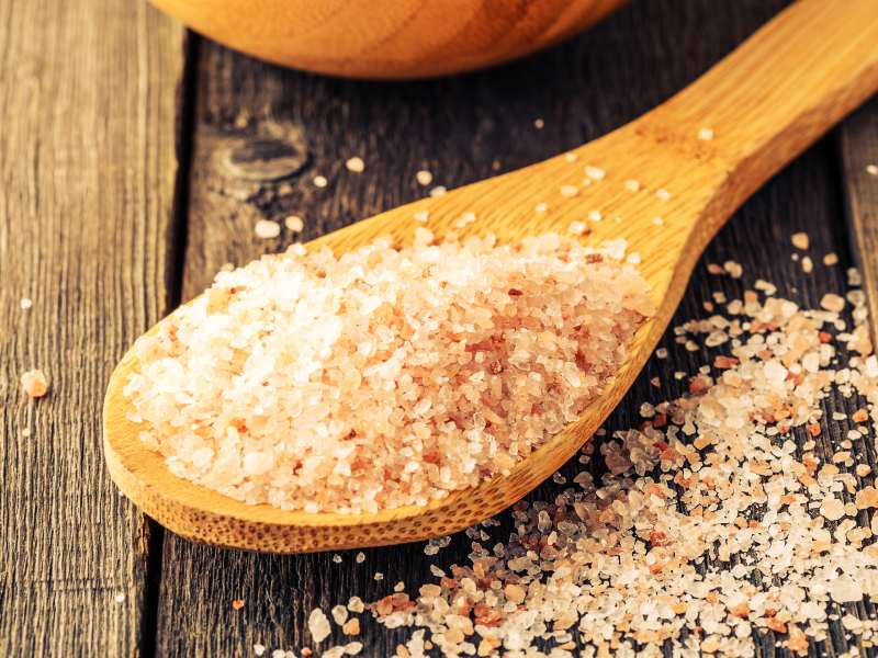 Pink salt crystals in a wooden spoon