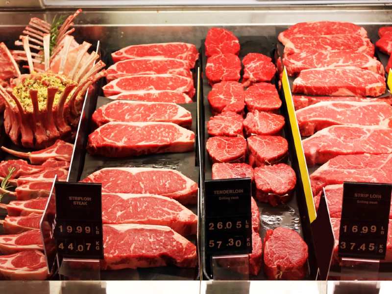 Assorted raw beef cuts displayed at a butcher counter