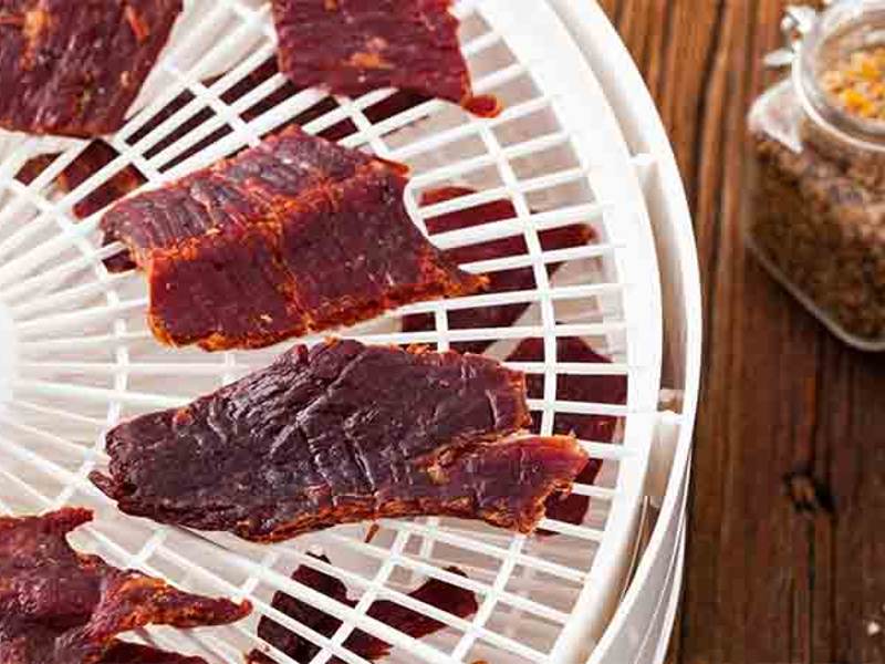 Seasoned beef strips on a round dehydrator tray