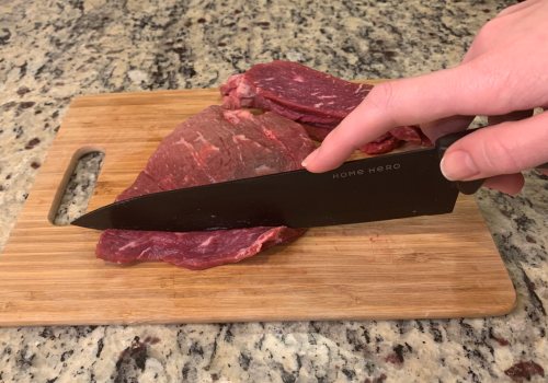A knife cutting chilled beef into thin strips