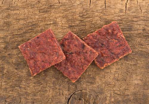 Three thin reddish snack squares on a wooden surface