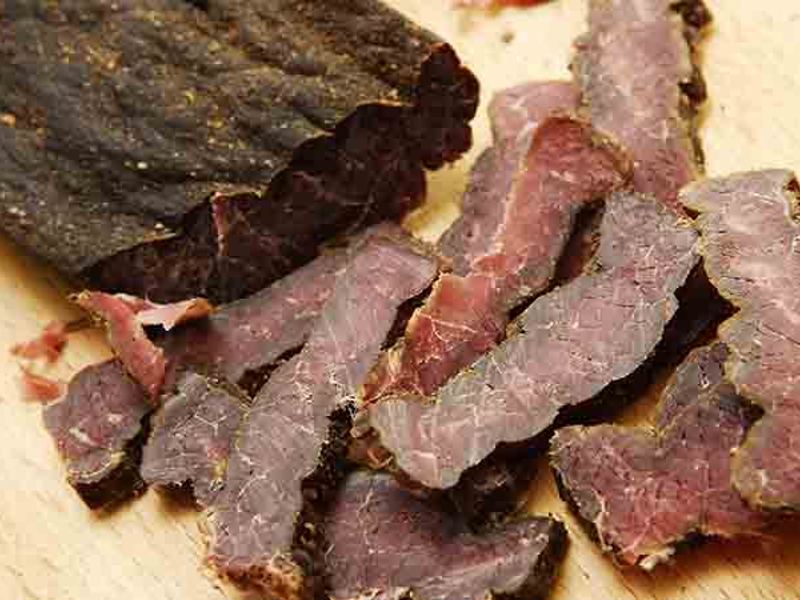 Thin slices of biltong beside a larger dried piece