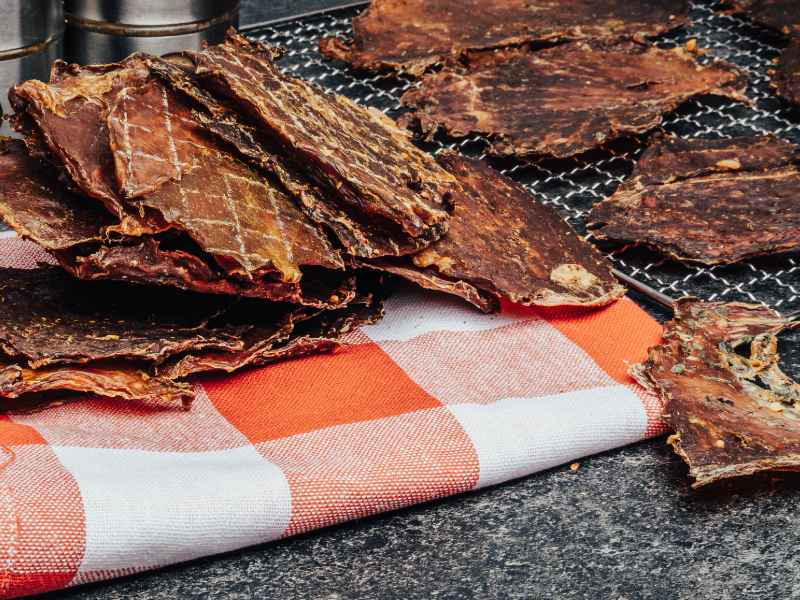 Large dried meat sheets on a rack over a striped towel