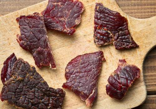 Thin beef jerky pieces spread over parchment on a board