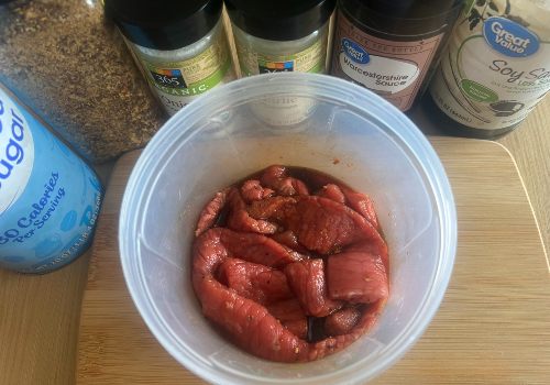 Beef strips coated in red-brown marinade in a round container