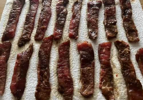 Marinated beef strips draining in rows on paper towels