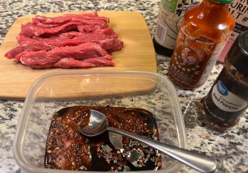 Chopped garlic and chili marinade beside sliced raw beef