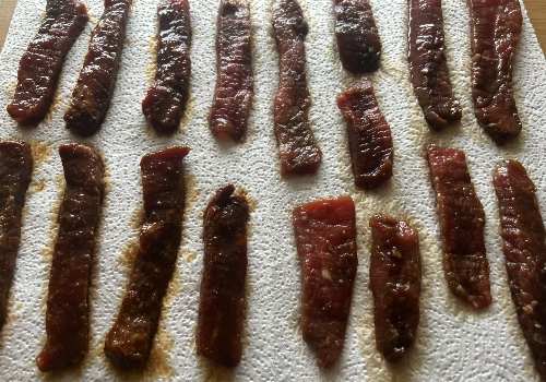 Marinated beef strips arranged in rows on paper towels