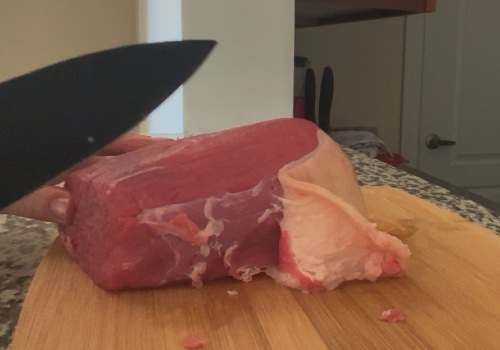 A knife beside beef with a pale strip of surface fat