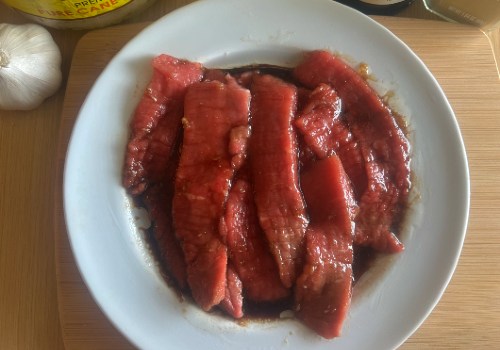 Beef strips coated in marinade in a white bowl