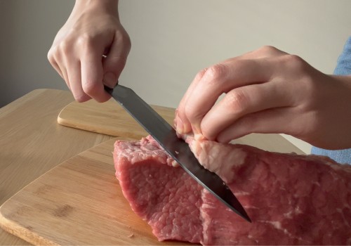 A cook trimming pale fat from a beef roast