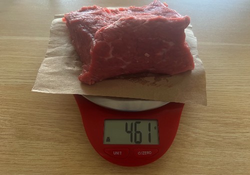 Raw bottom round beef on a scale reading 461 grams