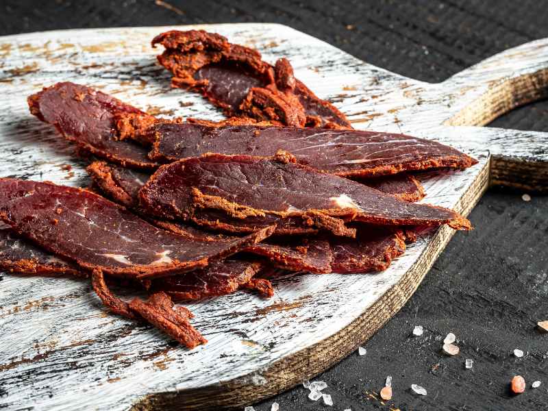 Sliced, spice-crusted dried beef on a wooden serving board