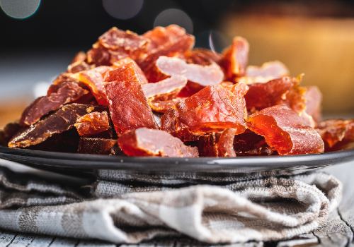 Reddish dried meat pieces piled on a black plate