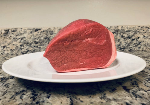 An eye of round roast on a white plate