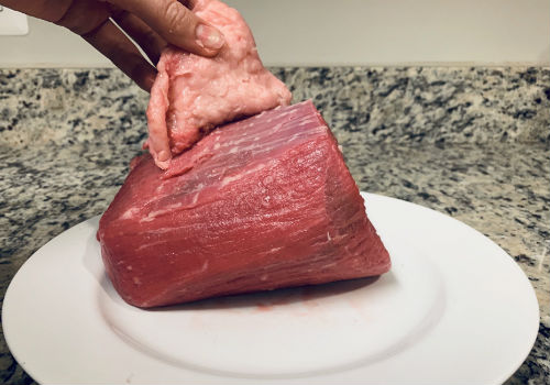 A strip of fat being lifted away from the beef roast