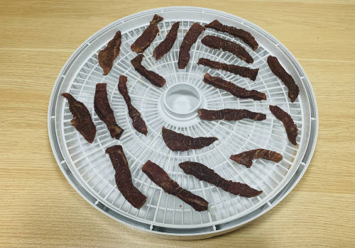 Small dried jerky strips on a round dehydrator tray