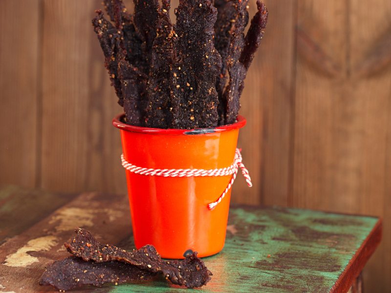 Long dried jerky strips standing in an orange cup