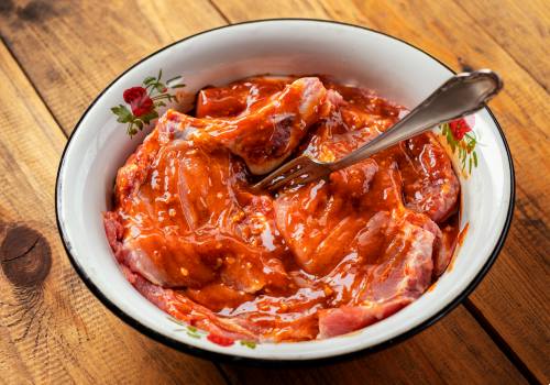 Raw meat coated in orange-red marinade in a bowl
