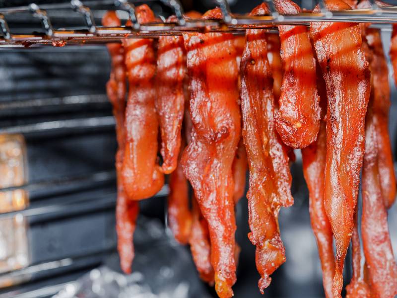 Seasoned meat strips hanging from an oven rack