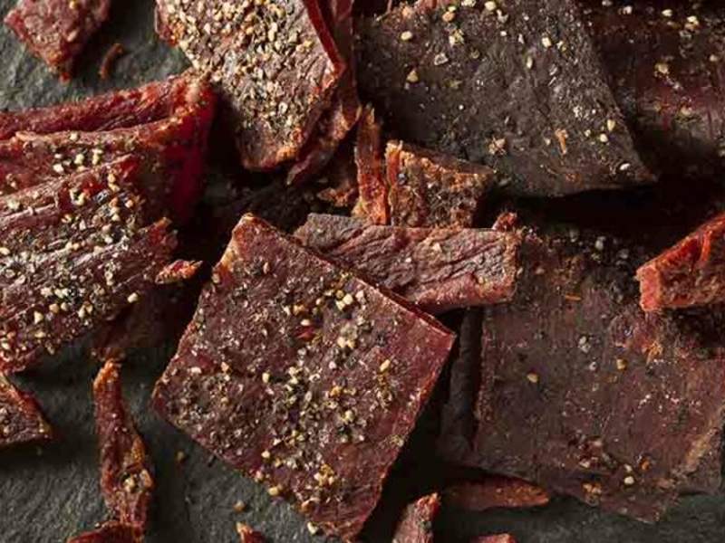 Seasoned jerky pieces with dark edges and visible pepper