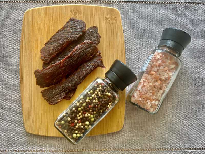 Jerky strips beside salt and pepper grinders