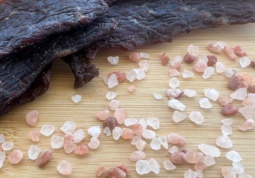 Coarse pink salt crystals beside dried beef
