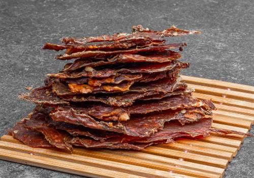 A tall stack of jerky sheets on a wooden board