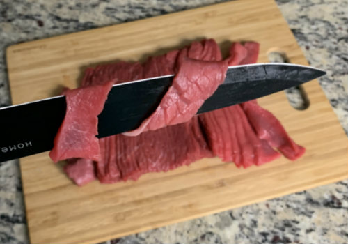 Thin bottom round strips draped over a knife blade