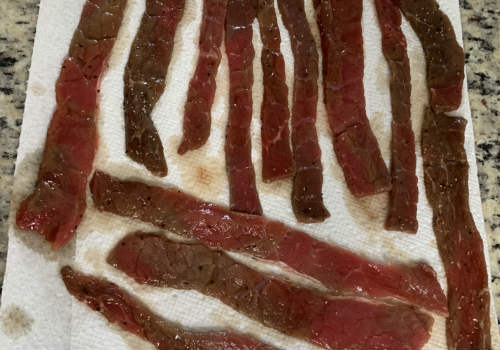 Long marinated beef strips resting on paper towels
