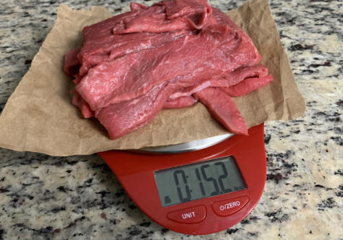 Raw beef strips weighed in ounces on a red scale