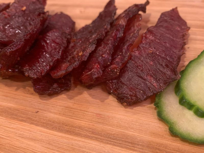 Dark beef jerky pieces beside cucumber slices