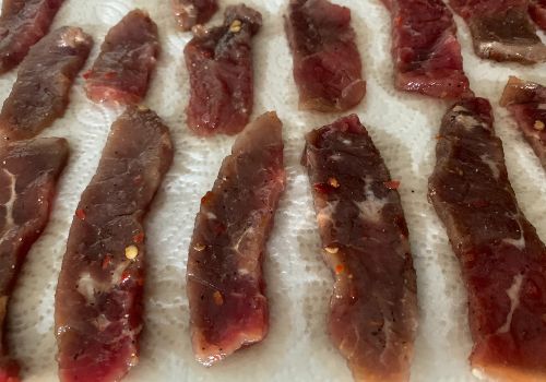 Marinated beef strips draining separately on paper towels