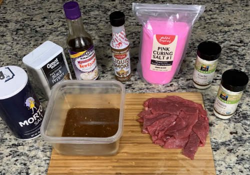 A container of teriyaki marinade beside raw beef slices