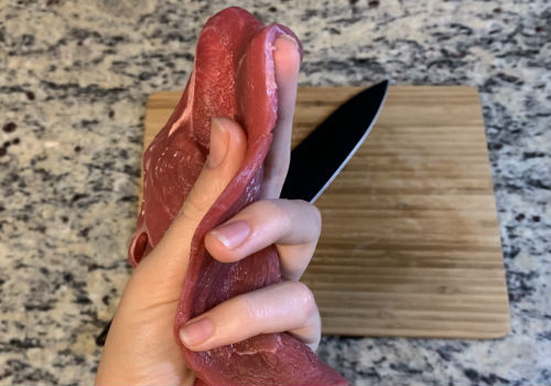 A hand holding thin sirloin tip slices