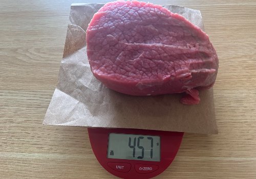 Raw beef on a scale reading 457 grams