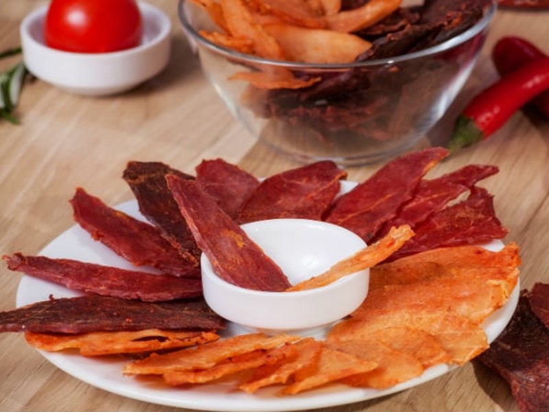 Red and orange dried meat strips arranged around a small dipping bowl