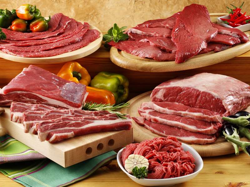 An assortment of raw meat cuts on boards and plates