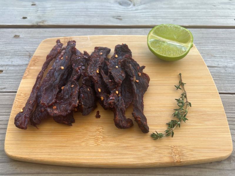 Chile-speckled jerky strips beside a lime half