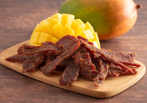 Beef jerky strips beside a cut mango