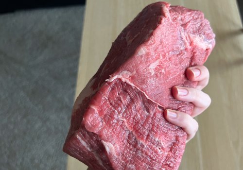 A hand holding a bottom round roast