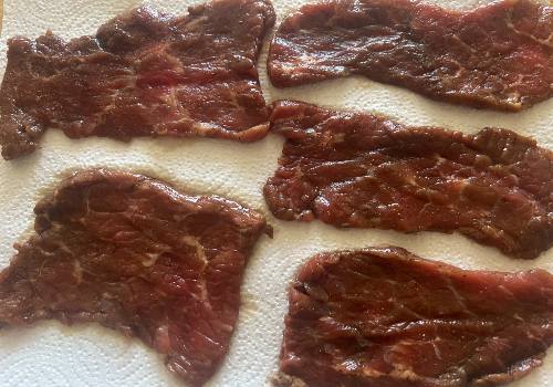 Marinated beef slices draining separately on paper towels