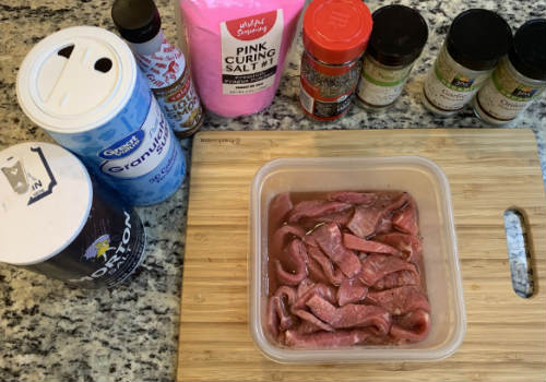 Beef strips coated in marinade in a rectangular container
