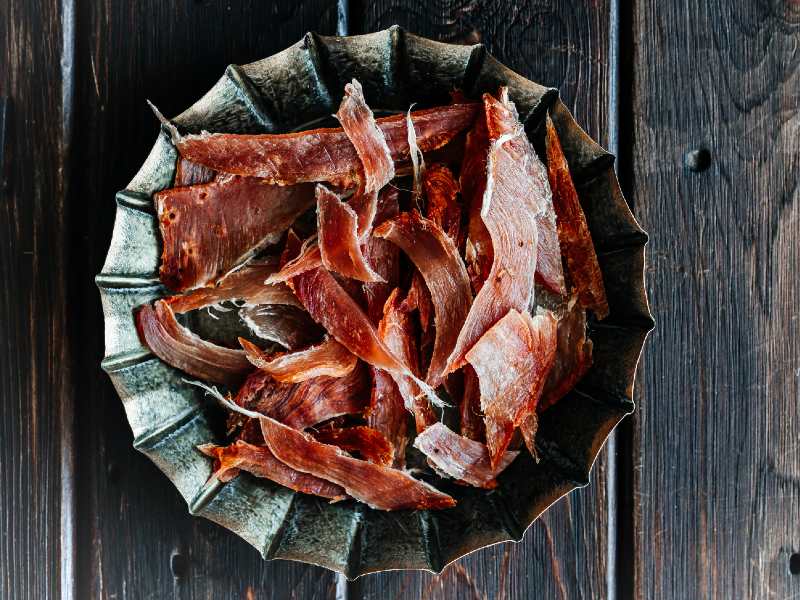 Thin dried meat strips piled on a dark plate