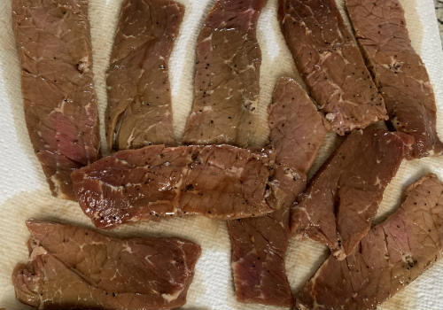 Pepper-marinated beef slices laid out on paper towels