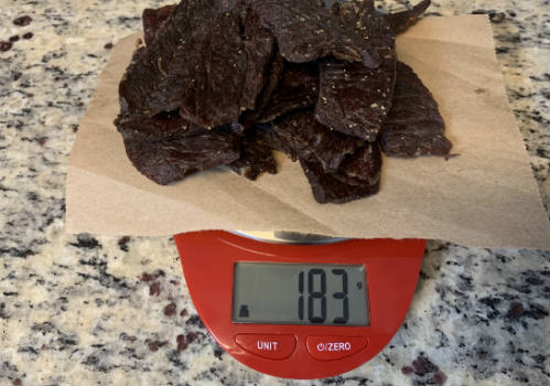 Finished peppered jerky on a scale reading 183 grams