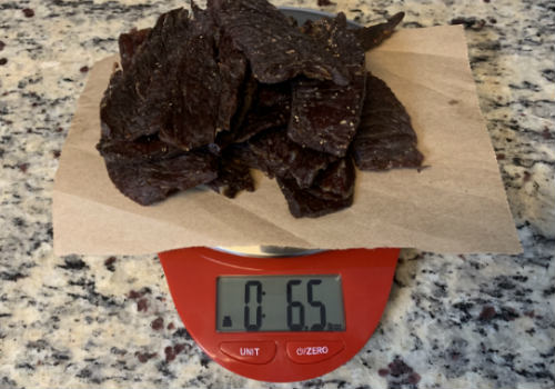 Finished peppered jerky on a scale showing 6.5 ounces