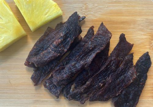 Jerky strips arranged beside pineapple wedges